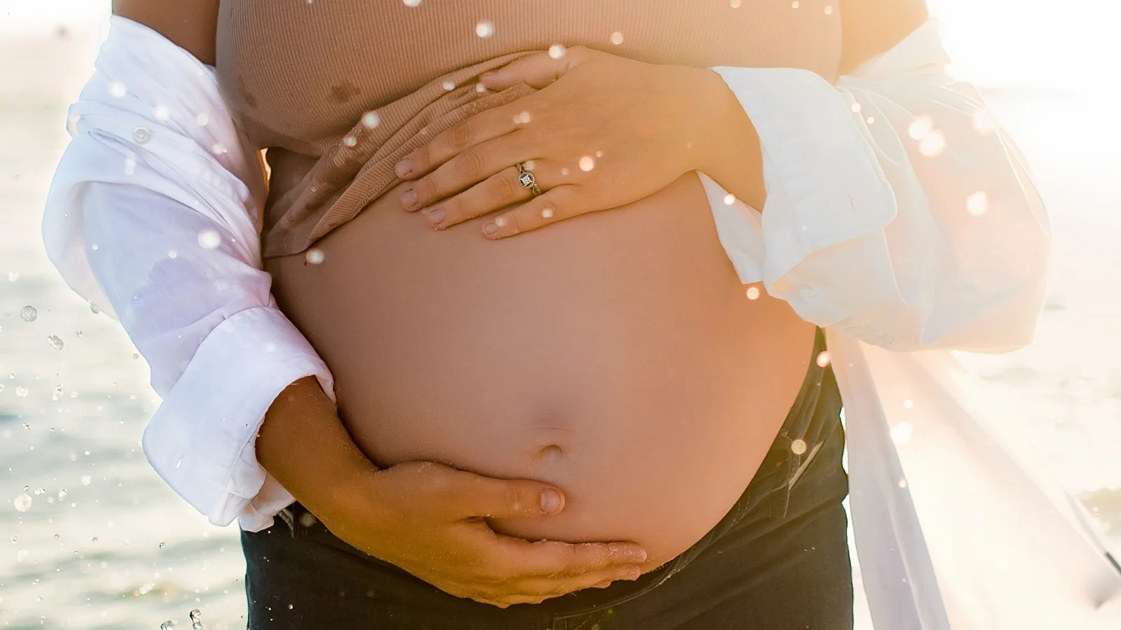 Close-up of an expecting mother's baby bump at sunset