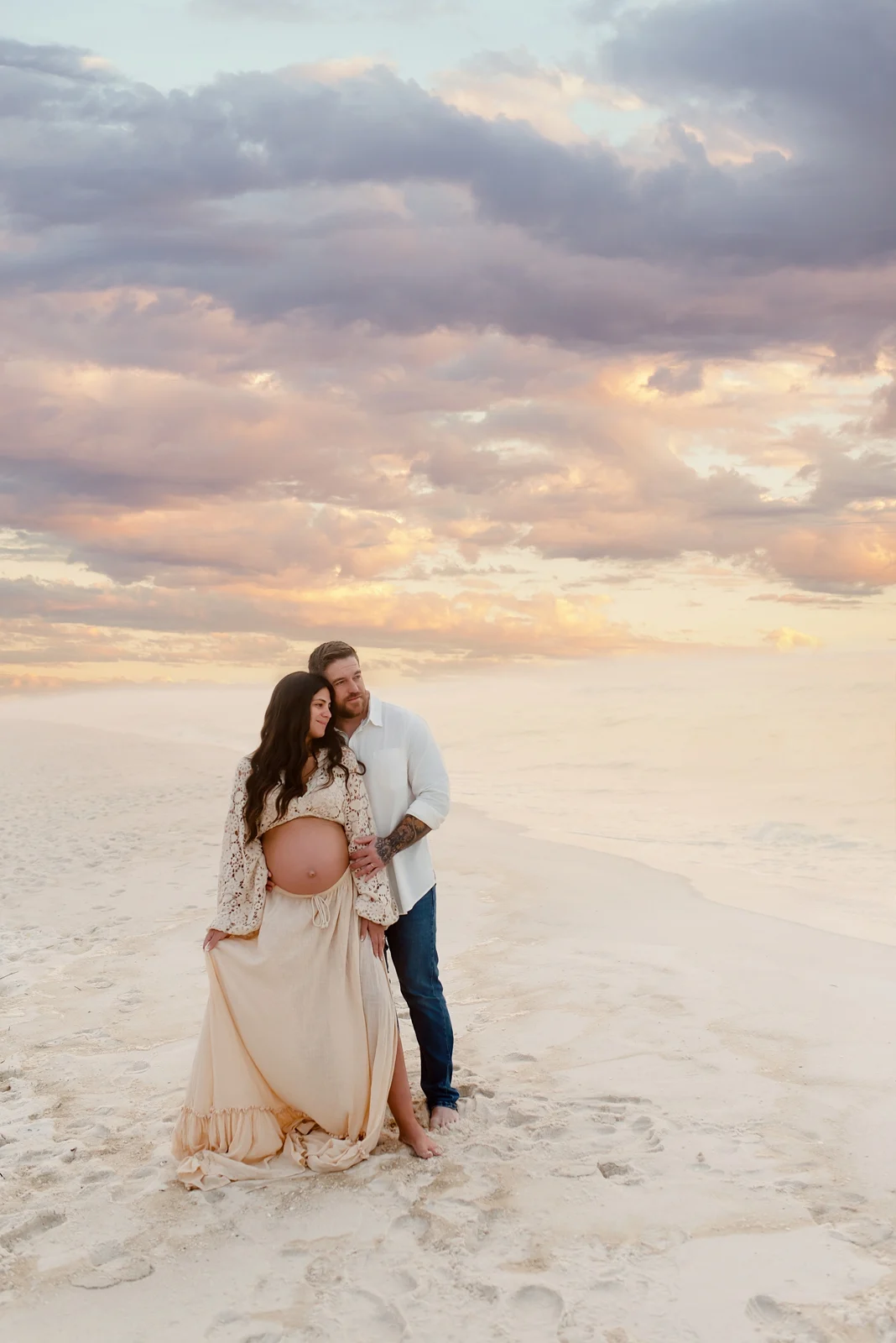 Expecting couple looking toward the Gulf at sunset