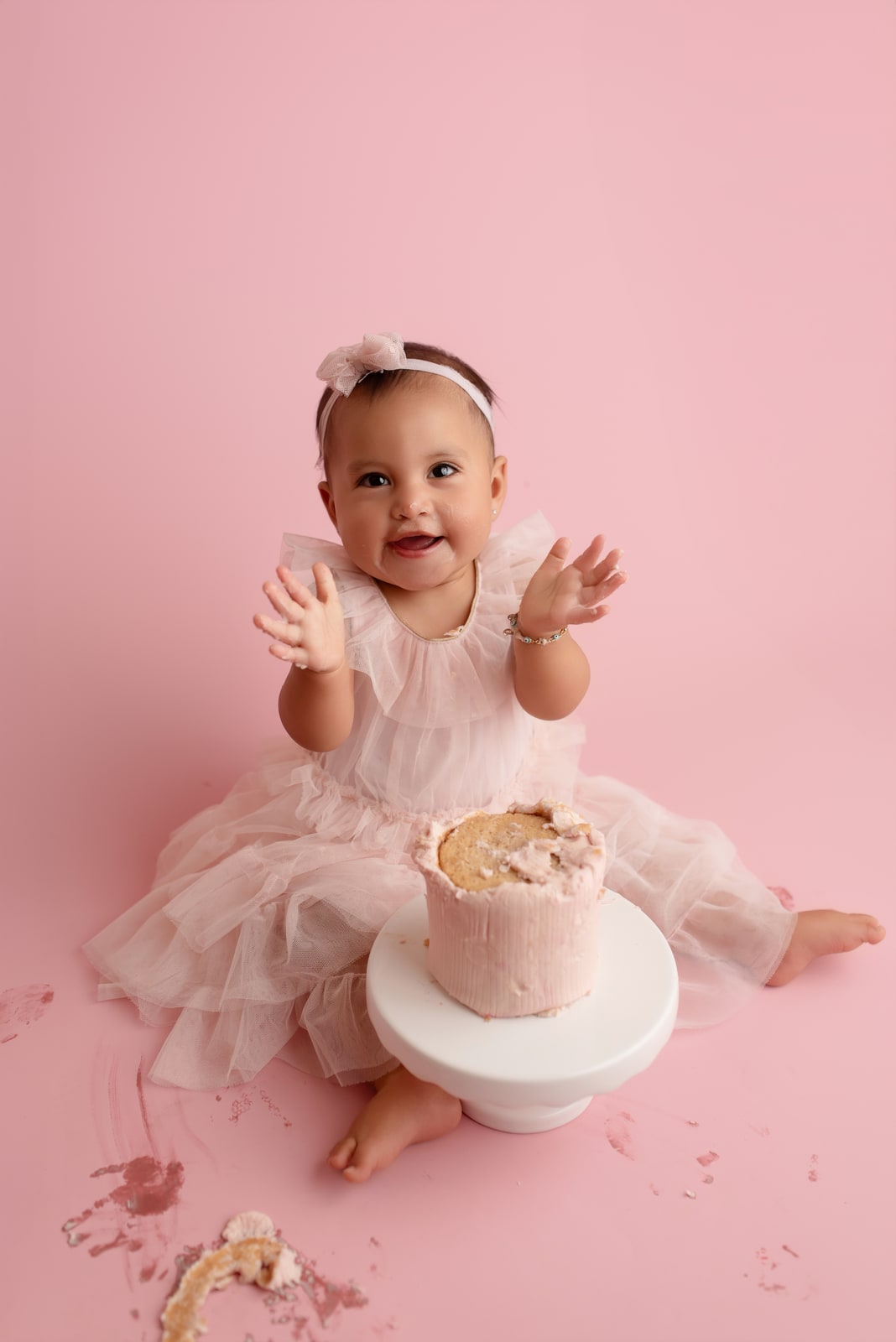 Toddler clapping during a pink cake smash session
