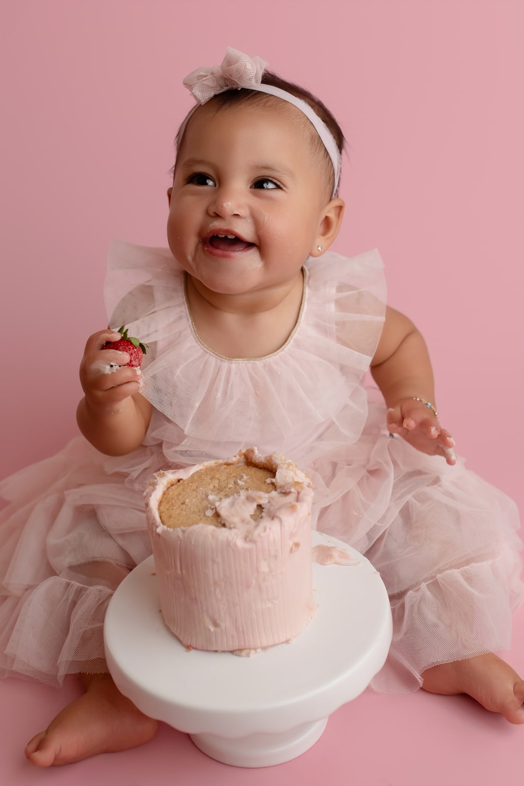 Toddler in a floral outfit eating birthday cake