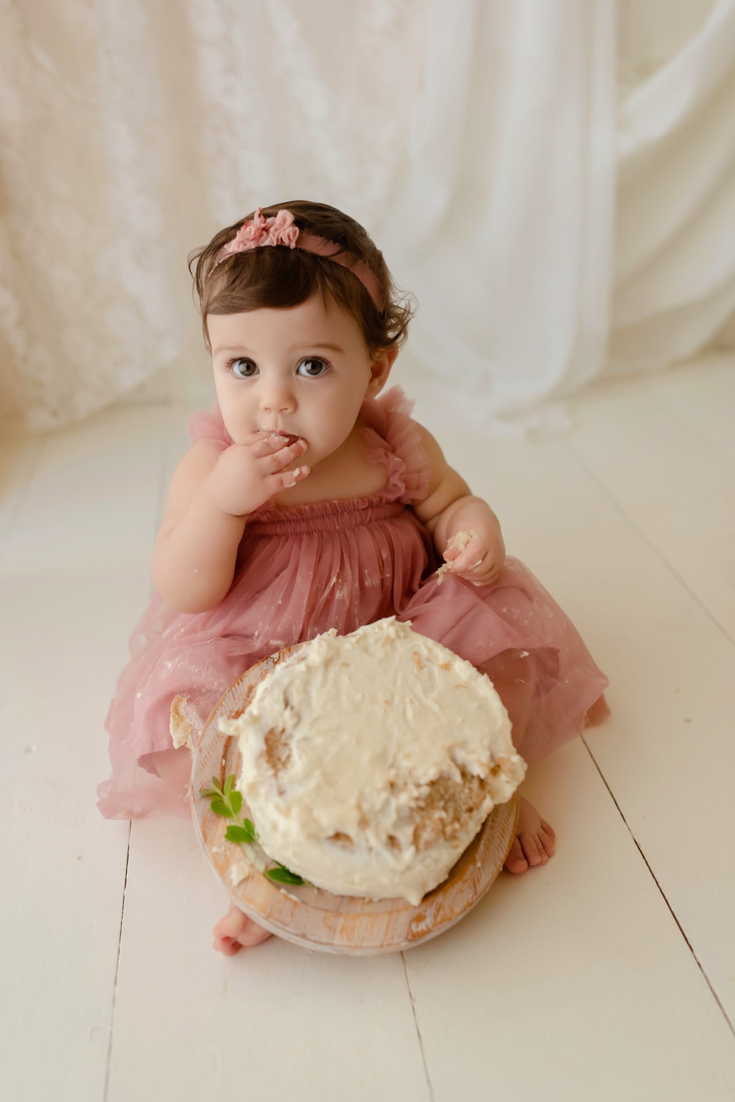 Toddler eating cake against a lace backdrop