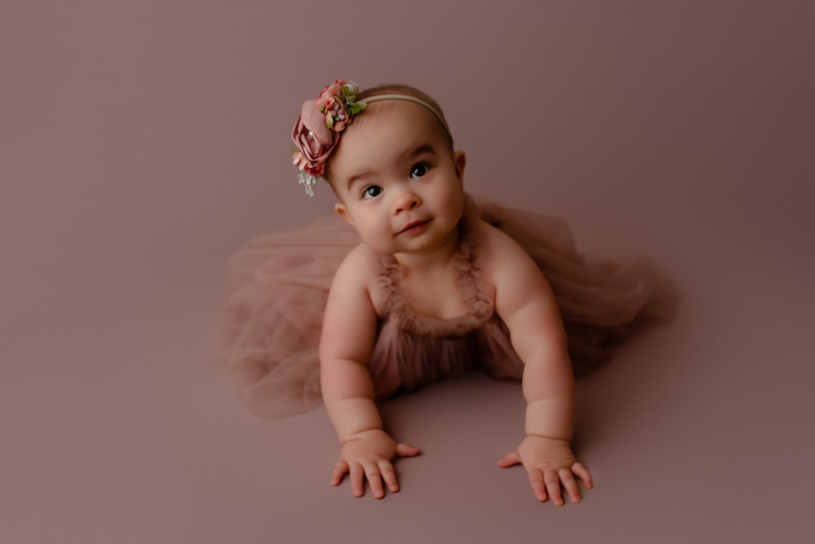 Baby crawling in a mauve tulle outfit with a floral headband